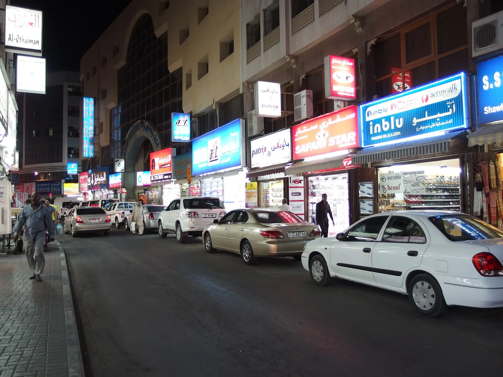 Busy evening street with shops and parked cars near the Gold Souk in Deira